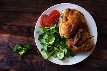 grilled half chicken, tomatoes and corn salad, dark rustic wood