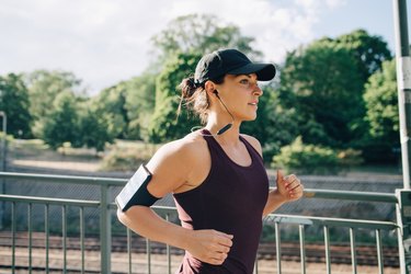 woman listening to music while running on a bridge outside