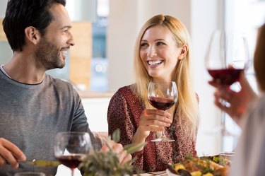 Laughing friends having dinner and eating food before drinking alcohol