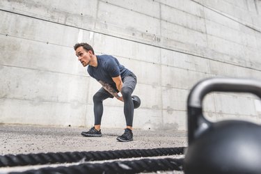 man doing kettlebell swing outside