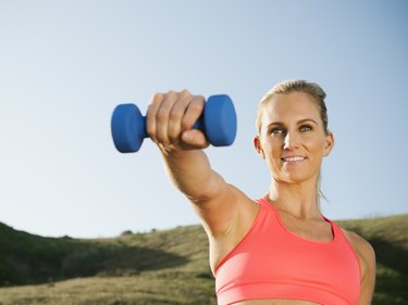 Woman doing double arm side or lateral raises to overhead