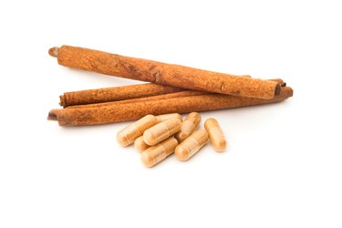 Cinnamon powder in pills with cinnamon sticks on white background