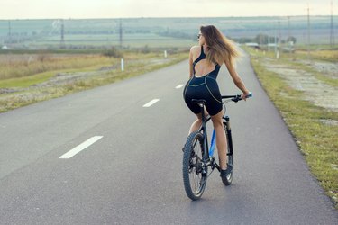 Girl on a mountain bike on offroad, beautiful portrait of a cyclist at sunset, Fitness girl rides a modern carbon fiber mountain bike.