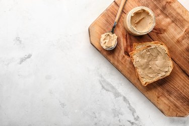 Composition with tasty toast and peanut butter on light table