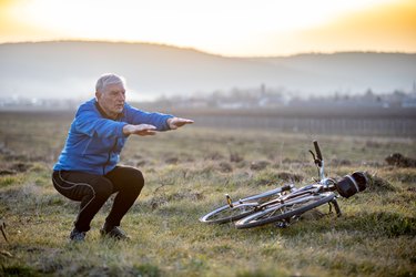 active senior man cyclist doing squats to warm up lower body