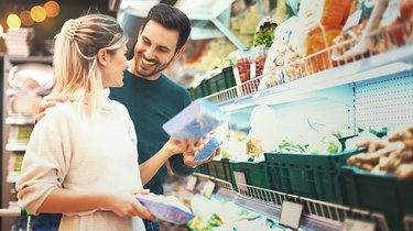 Couple shopping in supermarket for ingredients for their cheap meal plans