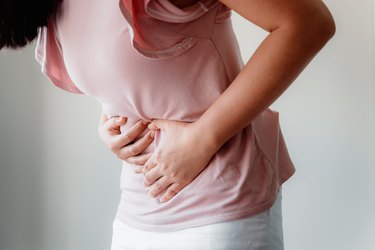 Midsection Of Woman With Stomachache Against Gray Background