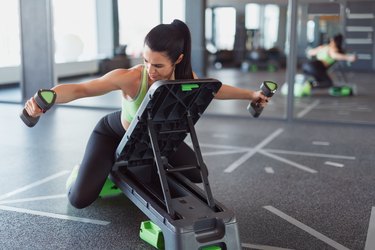 Woman training on step platform with dumbbells