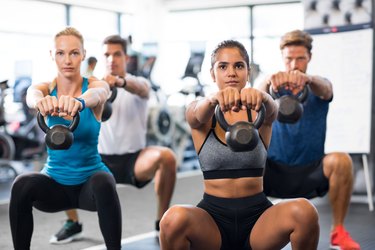 People with kettlebells squatting