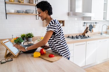 Young woman using a digital tablet while cooking