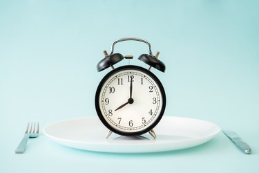 An alarm clock on a plate, intermittent fasting concept