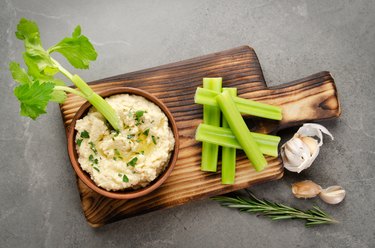 Flat lay view at vegetable Hummus dip dish topped with chickpeas and olive oil served with celery slices
