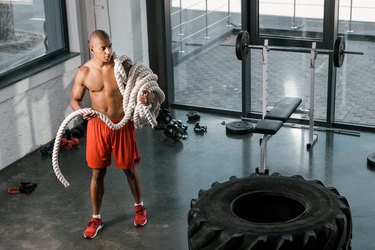 man in gym using battling ropes
