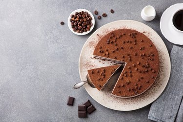 Tiramisu cake with chocolate decoration on a plate. Grey stone background. Top view. Copy space.