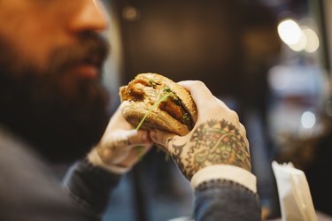 A man with tattoos eating a sandwich at a restaurant
