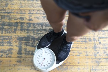 lower body of a man checking hypoglycemia's effect on weight gain or loss on a scale