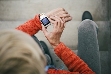 Senior woman checks her heart rate on smart watch taking a break