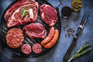 Various cuts of raw meat shot from above on a cast iron grill