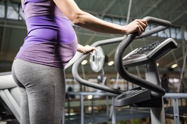 Pregnant person standing on a fitness machine