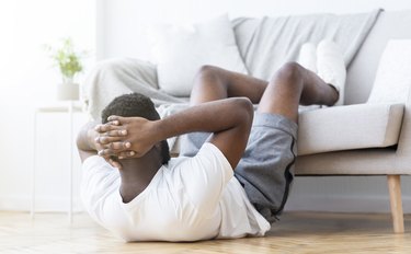 Black man doing abs training and crunches in living room