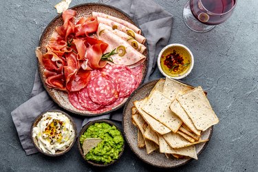 Antipasto. Meat platter, chips and sauces, red wine on gray background. Top view