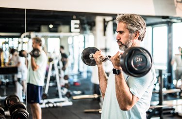 Mature man pushing weights in a health club.