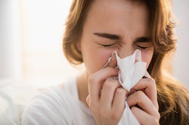 Woman blowing her nose on couch to remove deep boogers