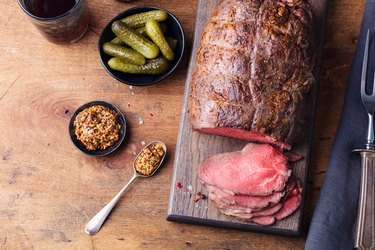 Roast beef on cutting board. Wooden background. Copy space. Top view.