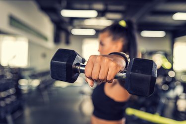 Woman in the gym doing a lateral dumbbell raise