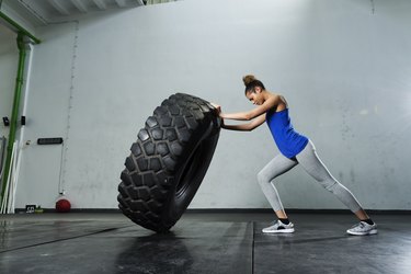 Young girl flipping tire at the gym to build muscles