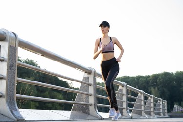 Young pretty woman with perfect slim body running outdoors. Fitness and running concept.