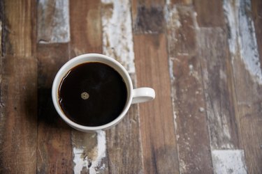 Black coffee in white cup on wooden table