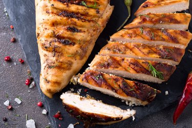 Grilled chicken fillets on slate plate on Gray concrete background. Healthy diet food concept, flat lay close up