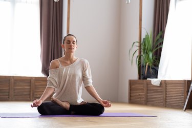 Charming young woman in meditation on the floor