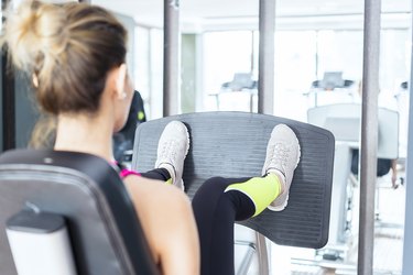 Female fitness instructor working out Leg press in health club