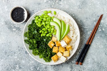 Cauliflower rice Buddha bowl with massaged kale, tofu, avocado and edamame beans. Vegan poke bowl