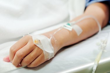 Midsection Of Woman With Iv Drip Lying On Bed In Hospital