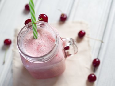 Milkshake or cherry smoothie on white wooden table. Wholesome breakfast