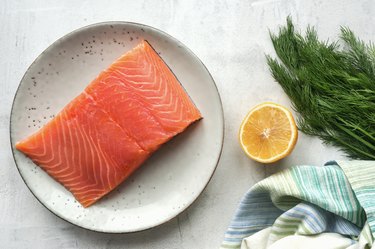 Fresh salmon steak, lemon and dill on concrete table.