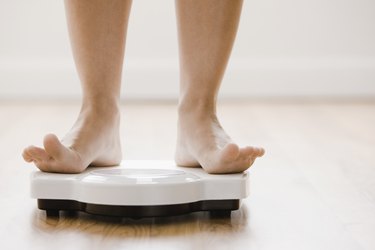 A woman's feet standing on a bathroom scale with toes lifted