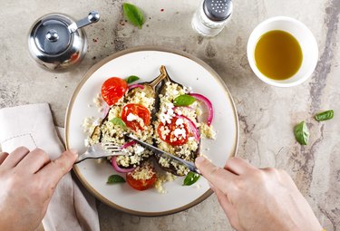 Baked eggplant stuffed with couscous, which is not gluten-free, plus tomatoes, feta and basil leaves