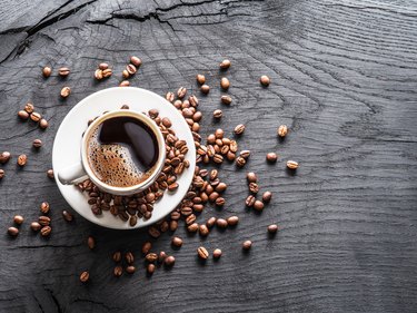 Cup of coffee surrounded by coffee beans.