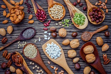 Various legumes and different kinds of nutshells in spoons. Waln