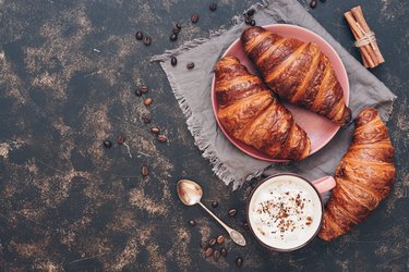 Croissants with coffee on a dark surface, top view, copy space.