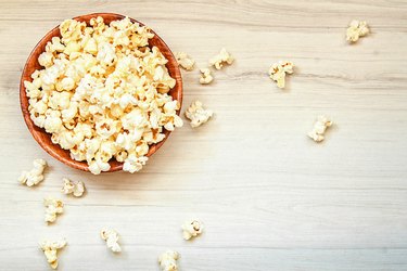 Salt popcorn in the wooden bowl on the wooden table.