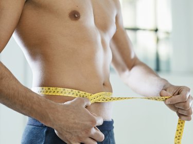 A man measuring his waist with a measuring tape to track weight loss