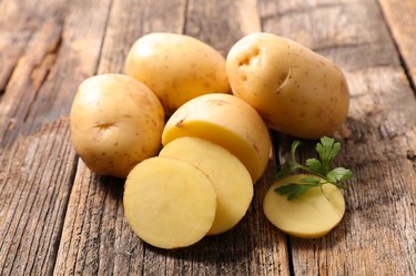 Cut and whole small white potatoes on wood