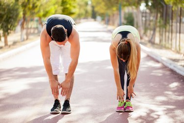 Man and woman outside stretching and trying to touch their toes