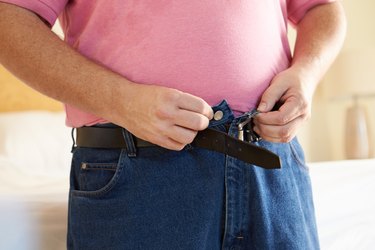 Close Up Of Overweight Man Trying To Fasten Trousers