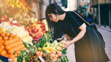 Woman Buying Fruits on Street Market to eat a plant based diet on a budget